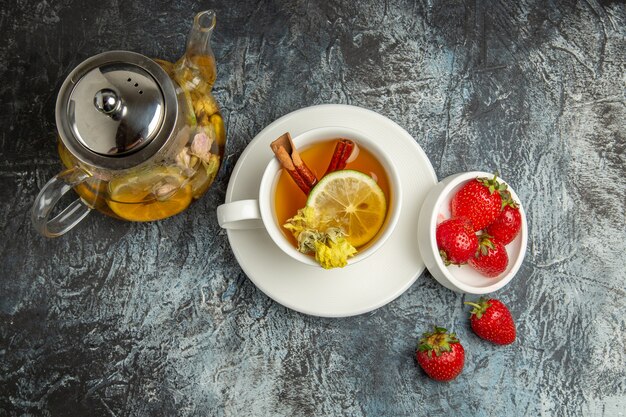 Вид сверху чашка чая с клубникой на темной поверхности фруктов и ягод чая