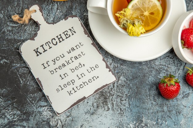 Free photo top view cup of tea with strawberries and funny desk on dark surface fruit tea berry