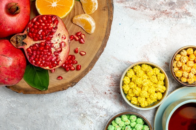 Top view cup of tea with sugar candies and fruits on white space