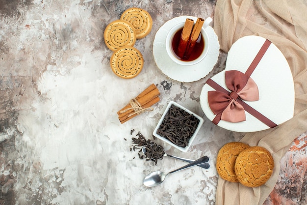 달콤한 비스킷이 포함된 상위 뷰 차 한잔과 밝은 배경 의식에 있는 선물 커피 설탕 쿠키 계피 색