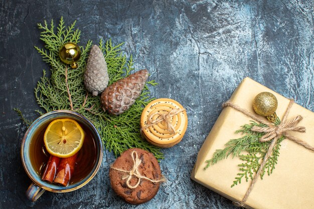 Top view cup of tea with sweet biscuits and present on light-dark background