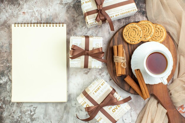 Вид сверху чашка чая со сладким печеньем и подарками на светлом фоне, церемония перерыва на печенье, цвет сахарного кофейного пирога