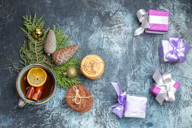 Free photo top view cup of tea with sweet biscuits and presents on light-dark background