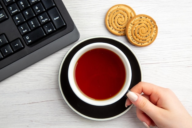 Top view cup of tea with sweet biscuits on white background sweet business keyboard female cake break job worker office cookie