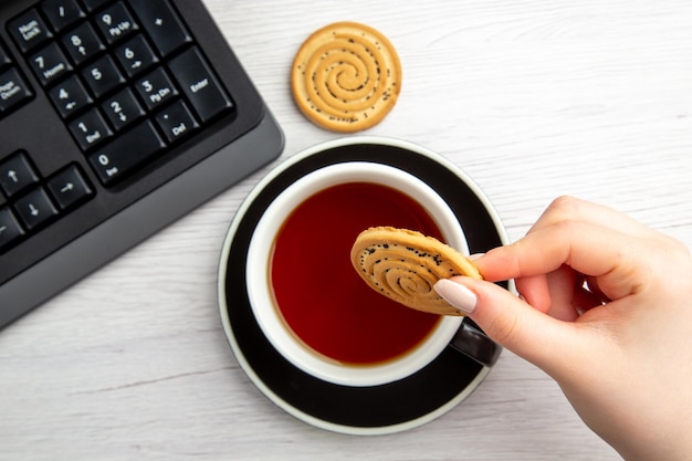 白い背景の上の甘いビスケットとお茶のトップビューカップ甘いビジネスキーボード女性のクッキーケーキ休憩ジョブワーカーオフィス