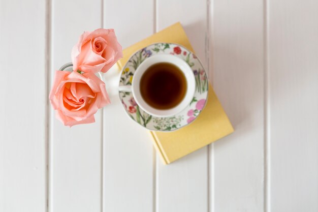 Top view of cup of tea with two decorative flowers