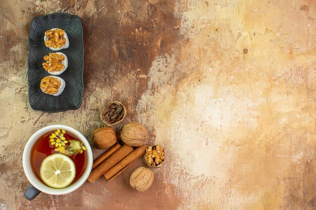 Top view cup of tea with walnuts candies on wooden desk