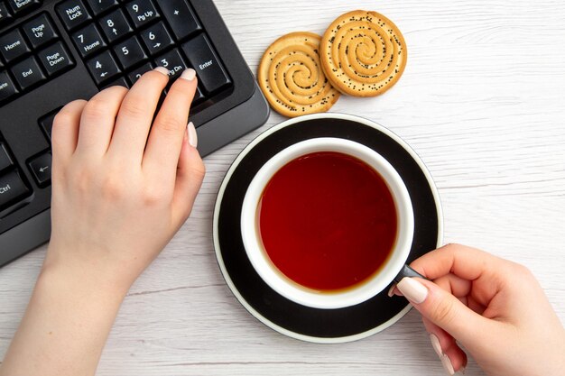 Вид сверху чашка чая женщина с клавиатурой и перерыв с чаем на белом фоне сладкий бизнес клавиатура женский печенье торт перерыв работа рабочий офис