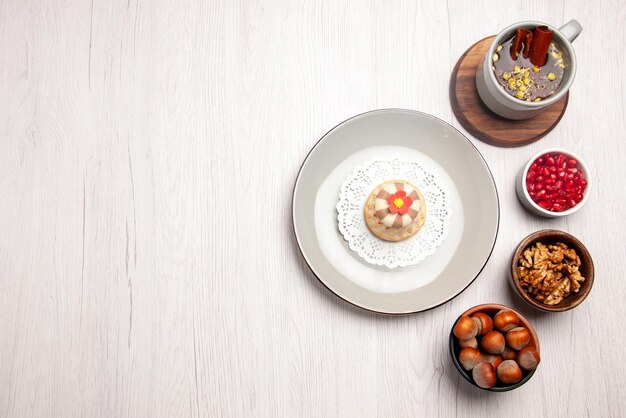 테이블에 석류와 헤이즐넛의 차 그릇 옆에 식욕을 돋우는 컵 케이크의 상위 뷰 컵 케이크와 차 접시
