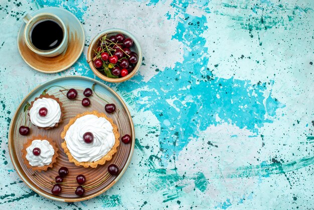 Top view of cupcake with cherries and cup of americano coffee