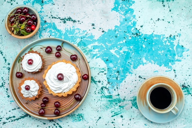 Free photo top view of cupcake with cream and cherries on top next to cup of americano coffee