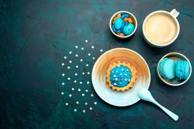 Вид сверху на кекс со звездами и голубым шоколадом рядом с чашкой кофе и миндальным печеньем