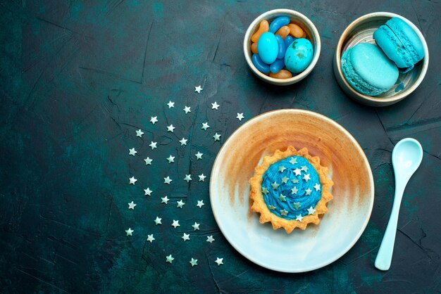 Top view of cupcake with stars decorations next to macaroons and sweets plates