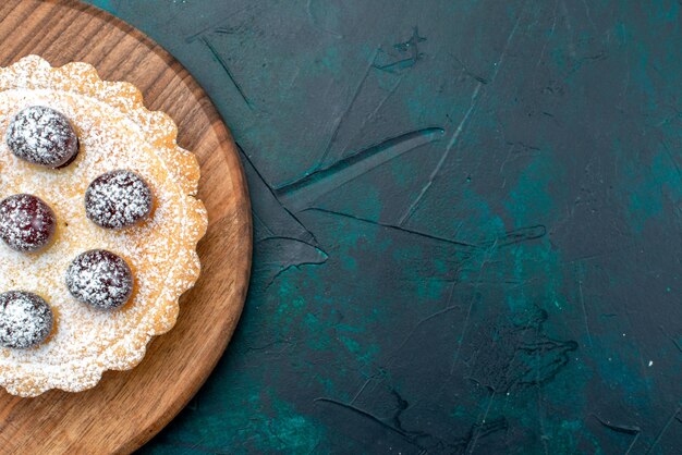 Top view of cupcake with sugar powder and delicious cherries on table