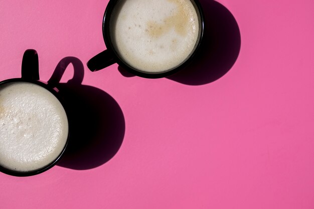 Top view cups of coffee on pink background