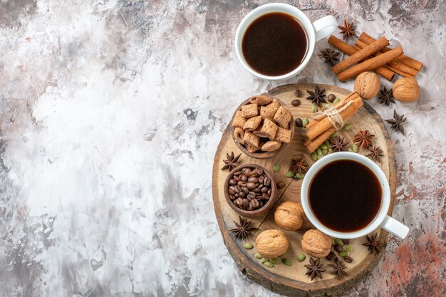 Top view cups of coffee with cinnamon and walnuts on light background sugar tea color cookie sweet cocoa