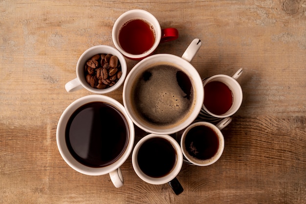 Foto gratuita tazze di caffè di vista superiore con fondo di legno