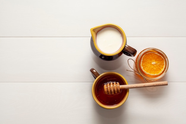 Top view cups with milk and tasty honey