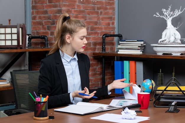 Free photo top view of curious lady sitting at a table and focused on something carefully in the office