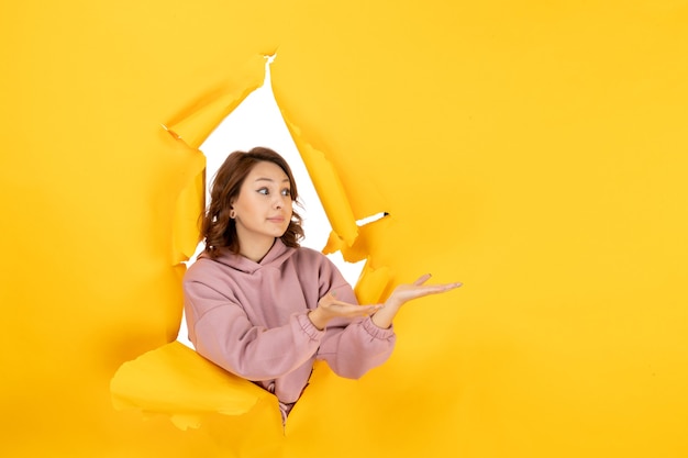 Top view of curious woman looking at something on the left side and free space on yellow torn