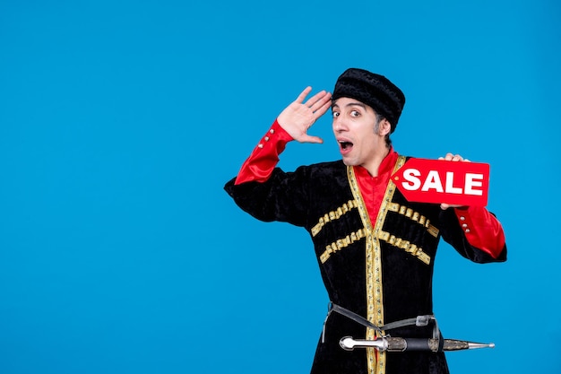 Top view of curious young man in traditional dress and showing sale icon on blue wave background