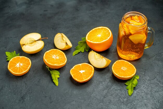 Top view cut cocktail cut oranges and apples on dark background