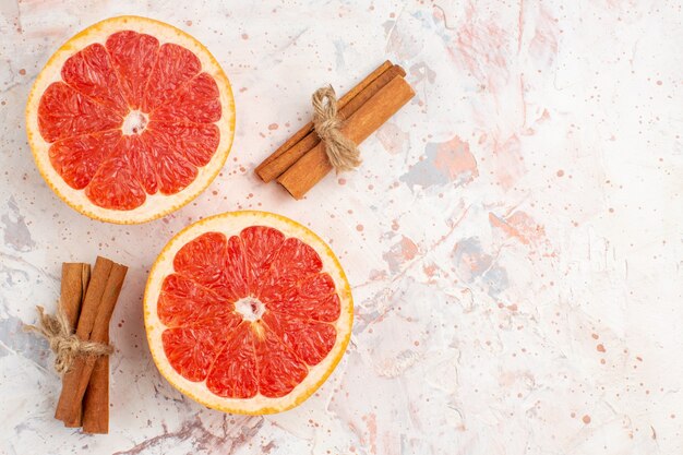 Top view cut grapefruits cinnamon sticks on nude surface copy space