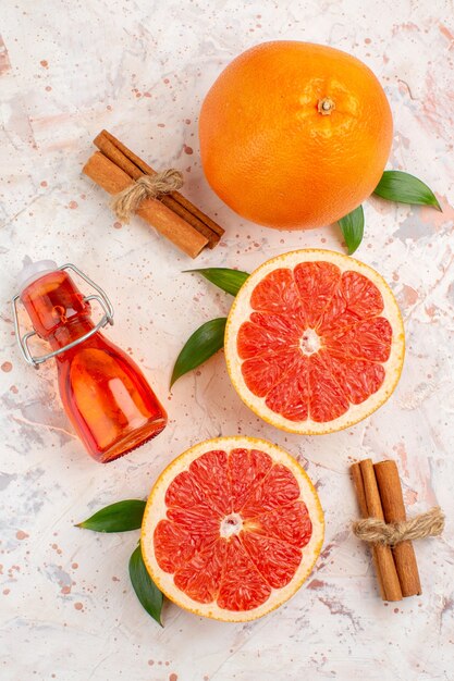 Top view cut grapefruits fresh grapefruit cinnamon bottle on nude surface