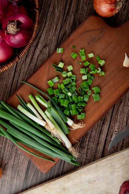 Top view of cut green onion on cutting board on wooden background