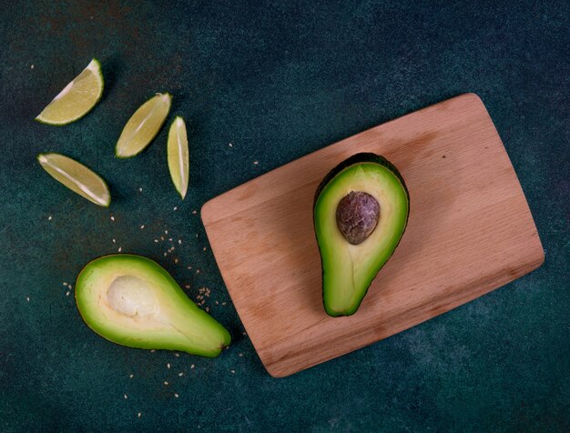 Top view cut in half avocado on a blackboard with lemon on a dark green background