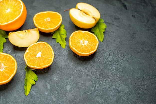 Top view cut oranges and apples on dark background