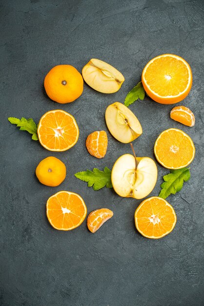 Top view cut oranges and apples on dark background