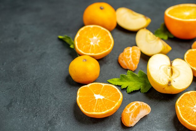 Top view cut oranges and apples on dark surface