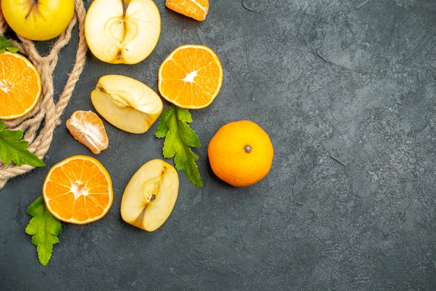 Top view cut oranges and apples on dark surface