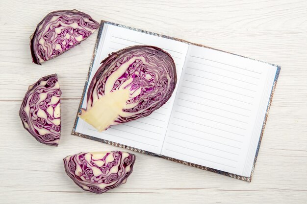 Top view cut red cabbage on notebook on wooden table