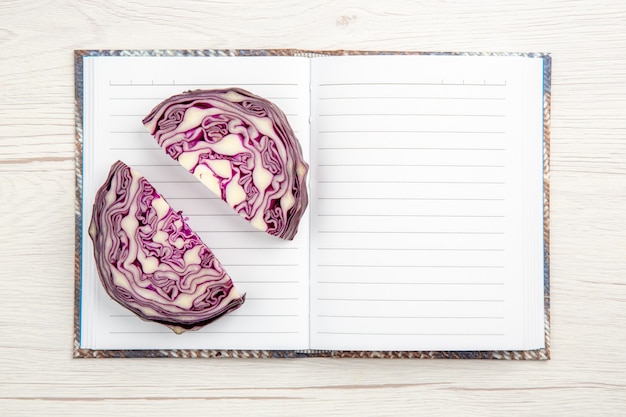 Free photo top view cut red cabbages on open notebook on wooden table