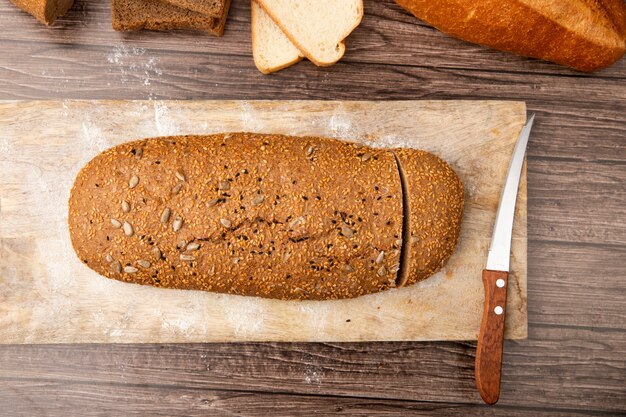 Top view of cut sandwich bread and knife on cutting board on wooden background