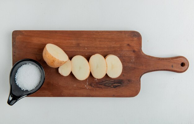 흰색 표면에 커팅 보드에 잘라 슬라이스 감자와 소금의 상위 뷰