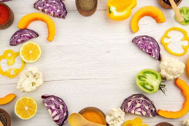 Top view cut vegetables cauliflower cut bell pepper cut pumpkin cut red cabbage cut green tomatoes on white wooden table free space