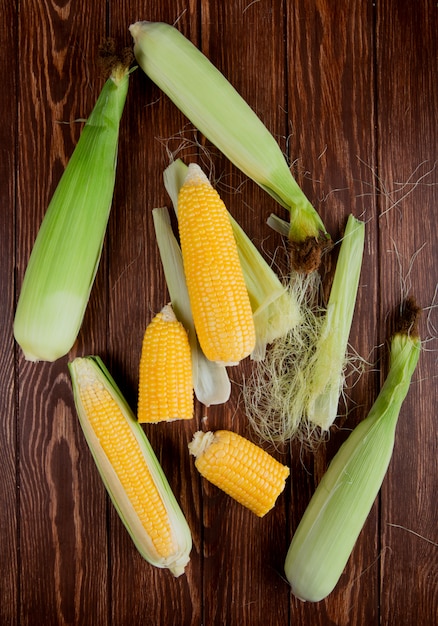 Top view of cut and whole corns with shell and silk on wooden surface