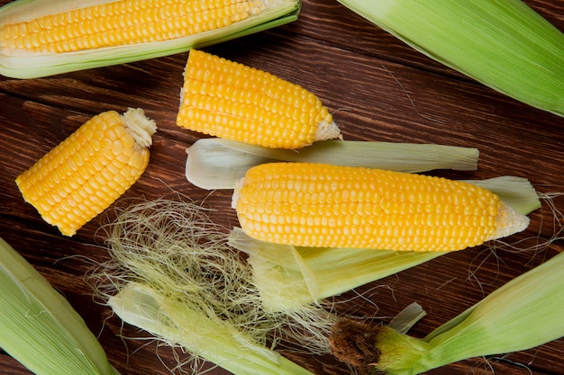 Top view of cut and whole corns with shell and silk on wooden surface