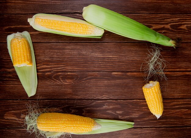 Top view of cut and whole corns with shell on wood with copy space