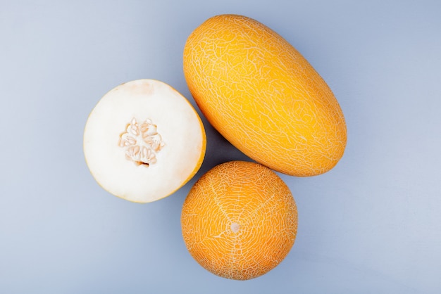 Top view of cut and whole melons on bluish gray background