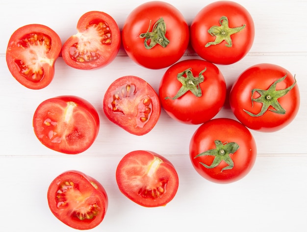 Top view of cut and whole tomatoes on wooden surface