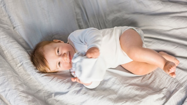 Free photo top view cute blonde baby in white bed