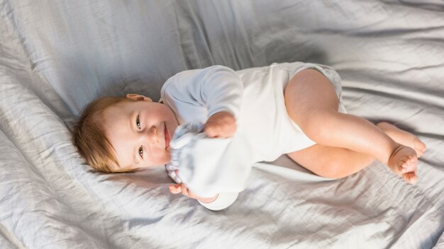 Top view cute blonde baby in white bed