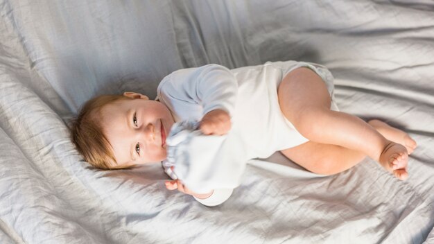 흰색 침대에서 상위 뷰 귀여운 금발 아기