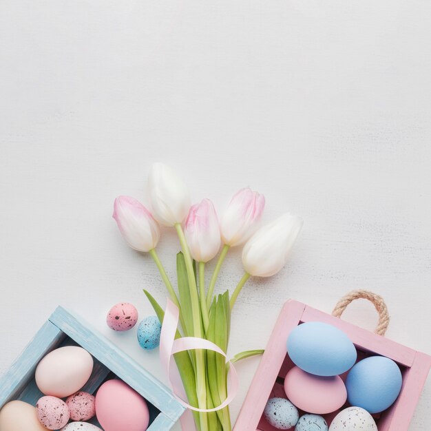 Top view of cute boxes with colorful easter eggs and bouquet of tulips