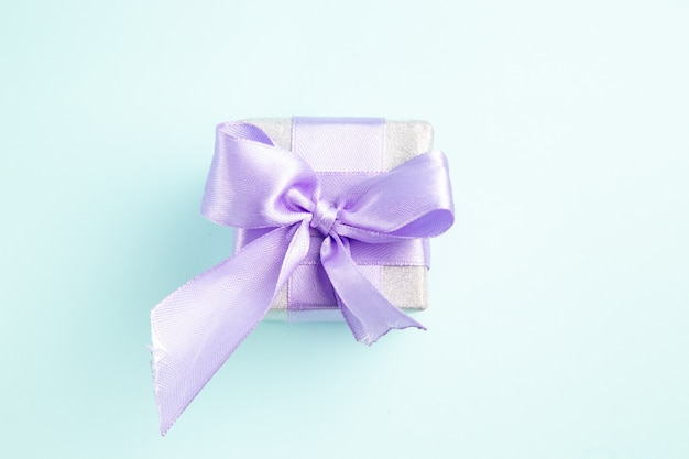 Free photo top view cute little present tied with bow on blue background