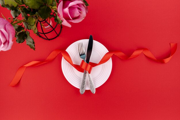 Top view of cutlery on plate with ribbon and roses